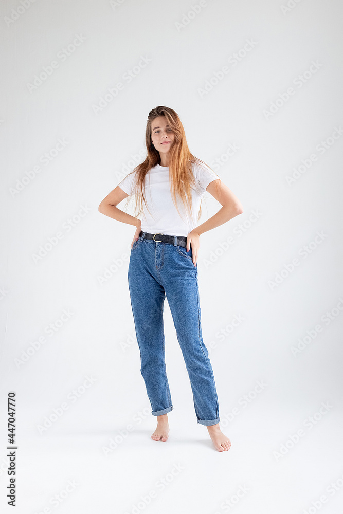 young attractive caucasian woman with long hair in t-shirt and blue jeans isolated on white studio background. skinny pretty female posing on cyclorama with bare feet. model tests of beautiful lady young attractive caucasian woman with long hair in t-shirt and blue jeans isolated on white studio background. skinny pretty female posing on cyclorama with bare feet. model tests of beautiful lady