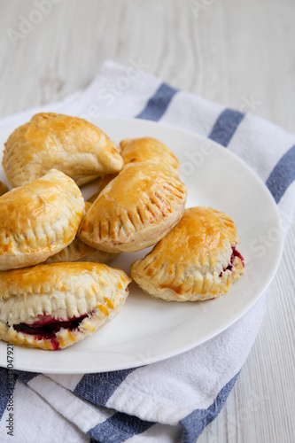 Homemade Cherry Hand Pies on a plate on a white wooden background, low angle view. Close-up.