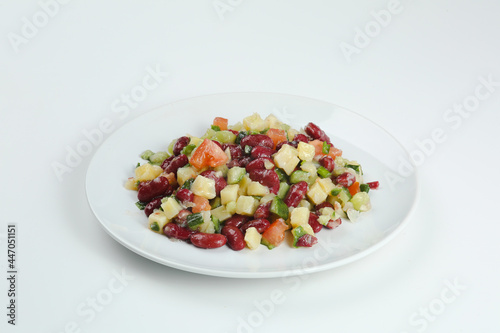 salad with beans, tomatoes, onions, potatoes closeup on white plate. bean salad isolated
