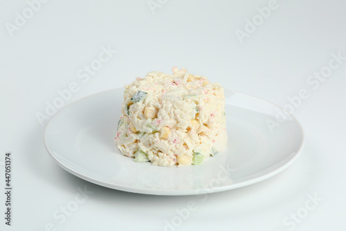 crab salad with rice on white plate closeup with copy space. Russian traditional salad with crab sticks isolated on white