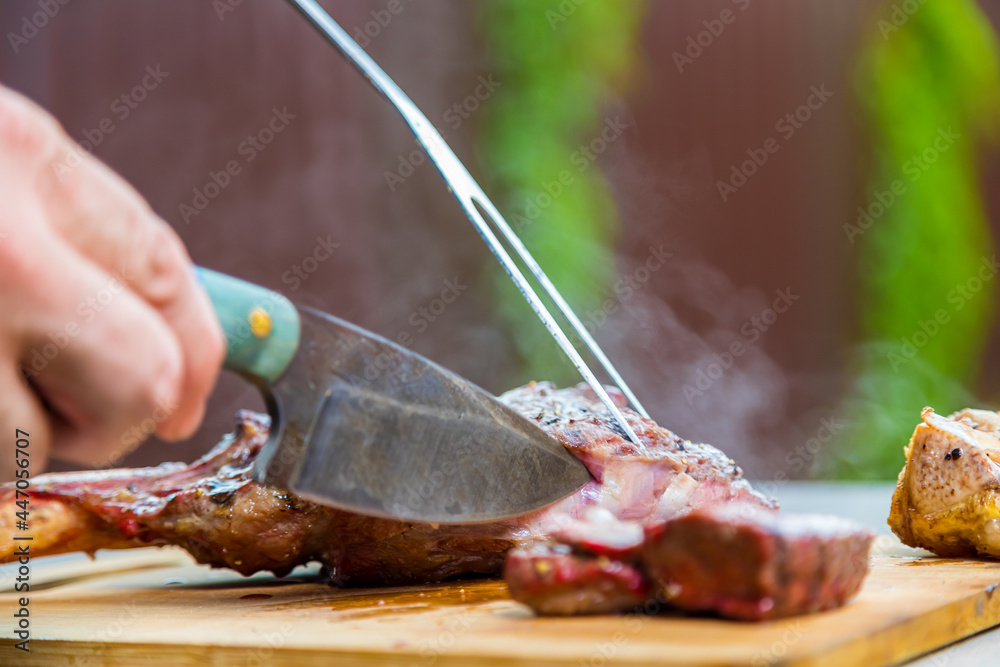 A man cuts cooked fried meat on a cutting board. Oven-baked meat for dinner.