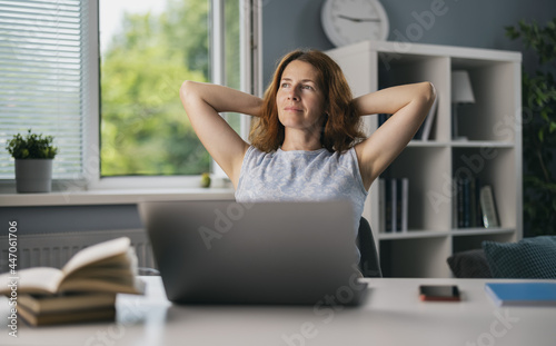 Foto Pretty female freelancer sitting on comfy chair with hands behind head and dreaming about vacation
