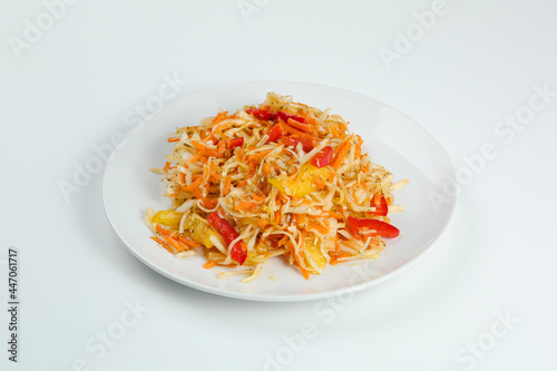 vitamin salad with carrot cabbage and pepper closeup on white plate. fresh summer salad isolated on white