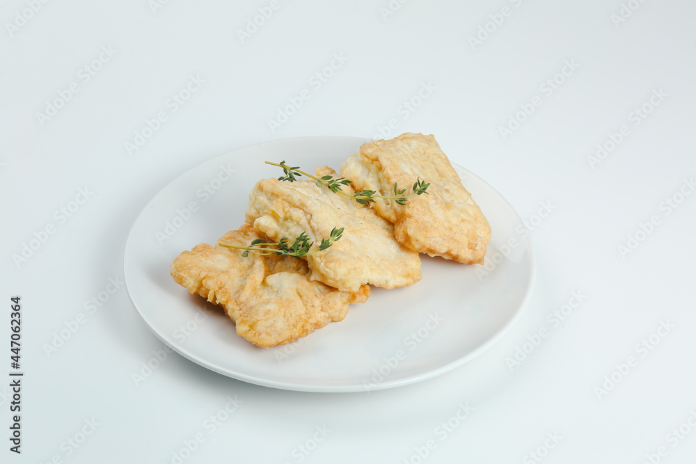 fillet of fish in batter on white plate closeup isolated on white background.