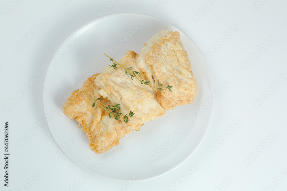 fillet of fish in batter on white plate closeup isolated on white background.