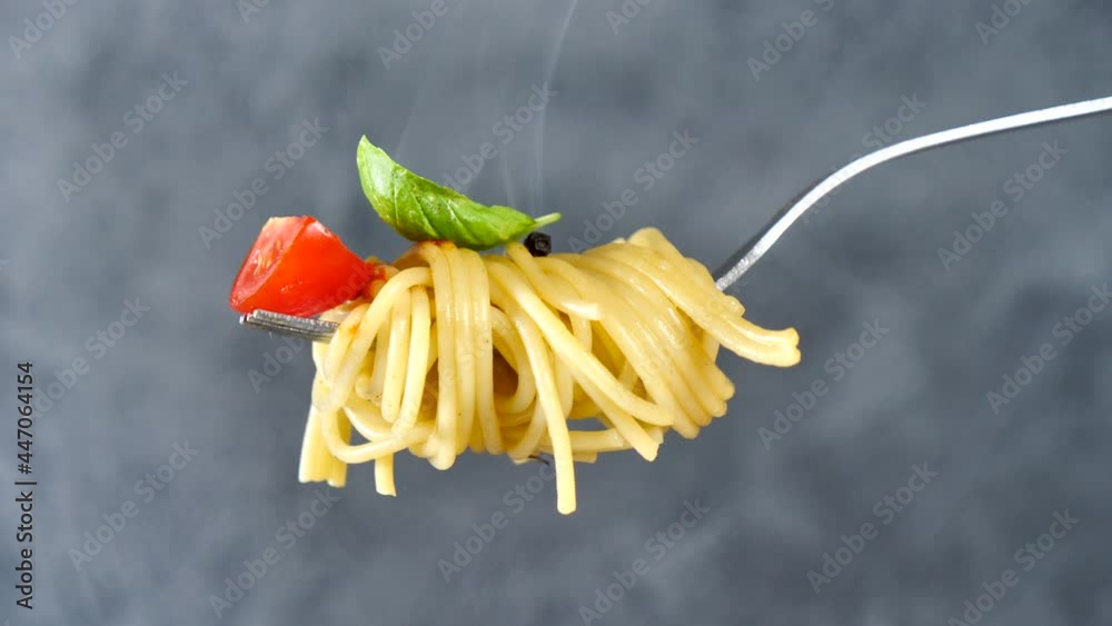 fork with spaghetti, tomato and basil with smoke