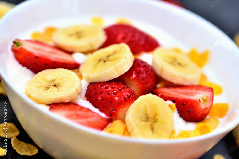 Healthy fruit bowl with yogurt, banana, strawberries and cornflakes. Glass jugs with cow milk. Close-up. Healthy fruit bowl with yogurt, banana, strawberries and cornflakes. Glass jugs with cow milk. Close-up.