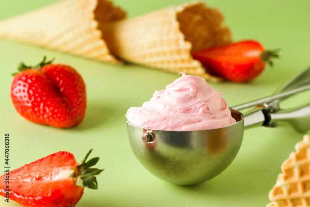 Strawberry ice cream in a special spoon. Cold summer natural dessert. Fresh strawberries and waffle cones on a green background.