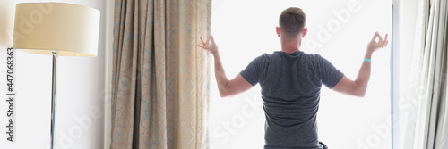 Man stands in lotus position by window