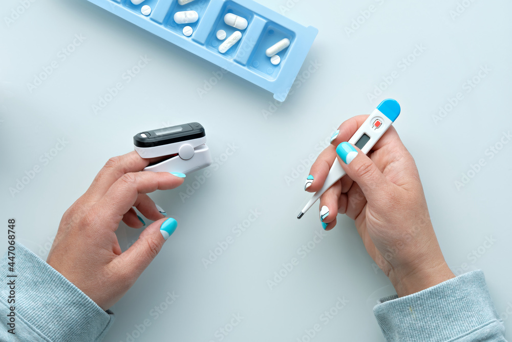Patient hands with pills and pulse oximeter, finger digital device to