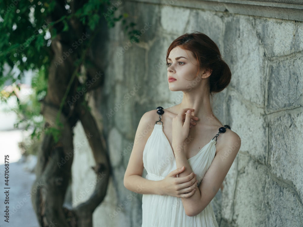 Obraz premium Woman in white dress near tree stone wall decoration lifestyle