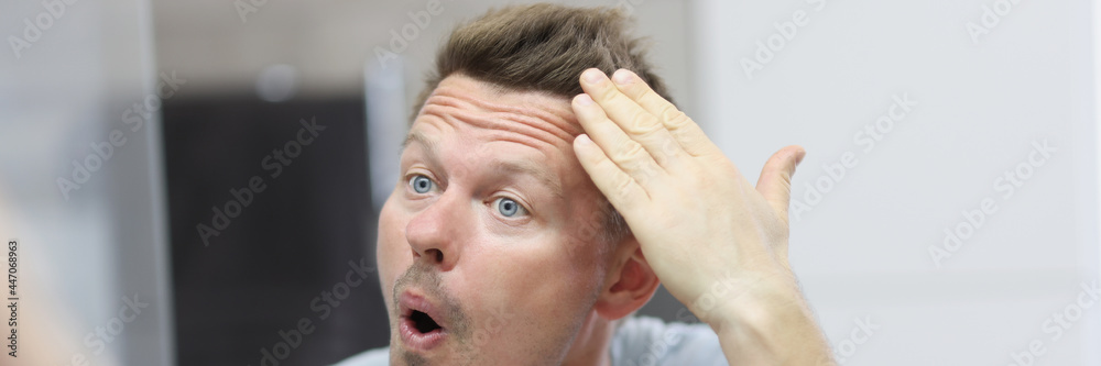 Obraz premium Narcissistic man in front of mirror does his hair