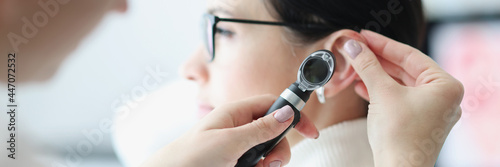 Otorhinolaryngologist examines patient ear with an otoscope photo