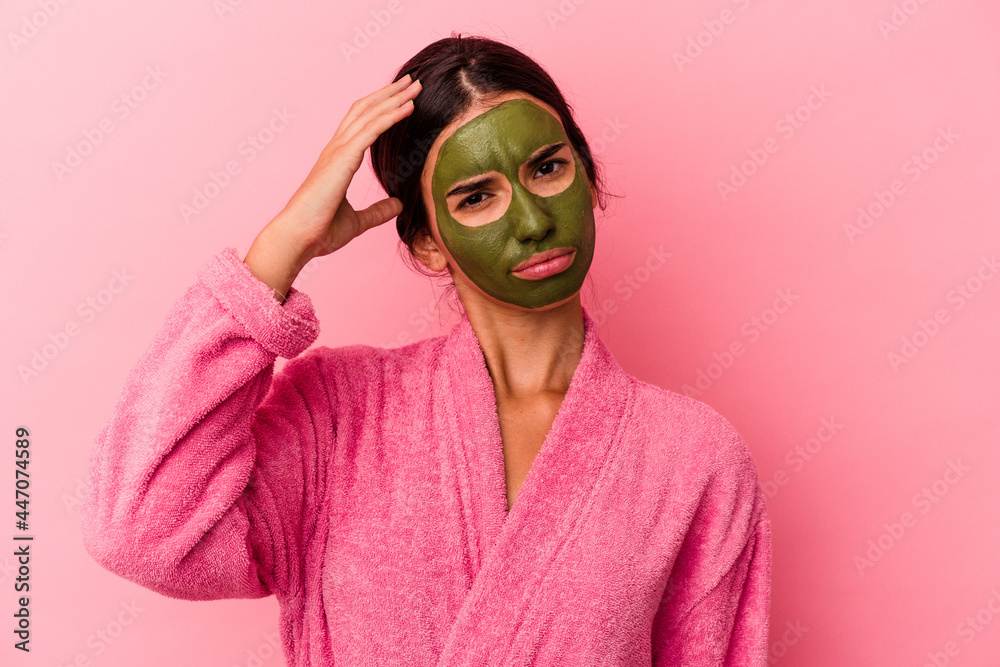 Young caucasian woman wearing a bathrobe and facial mask isolated on pink background being shocked, she has remembered important meeting.