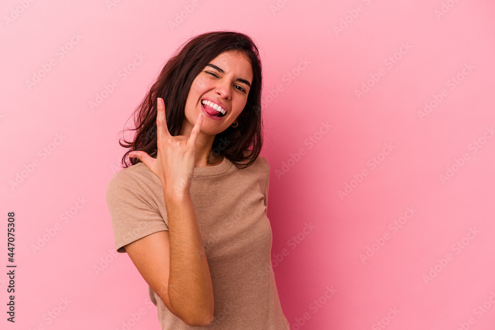 Young caucasian woman isolated on pink background showing rock gesture with fingers Young caucasian woman isolated on pink background showing rock gesture with fingers