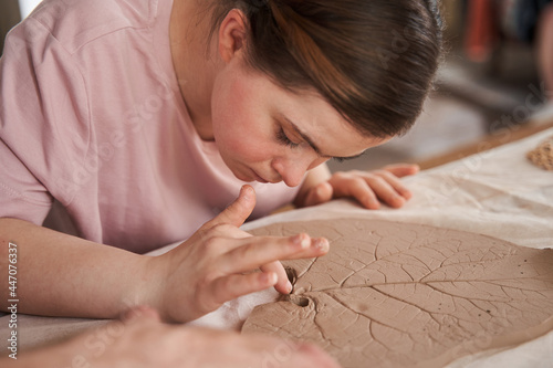 Girl with special needs looking at the clay with texture and touching it with the finger