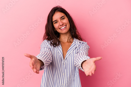 Young caucasian woman isolated on pink background showing a welcome expression. © Asier