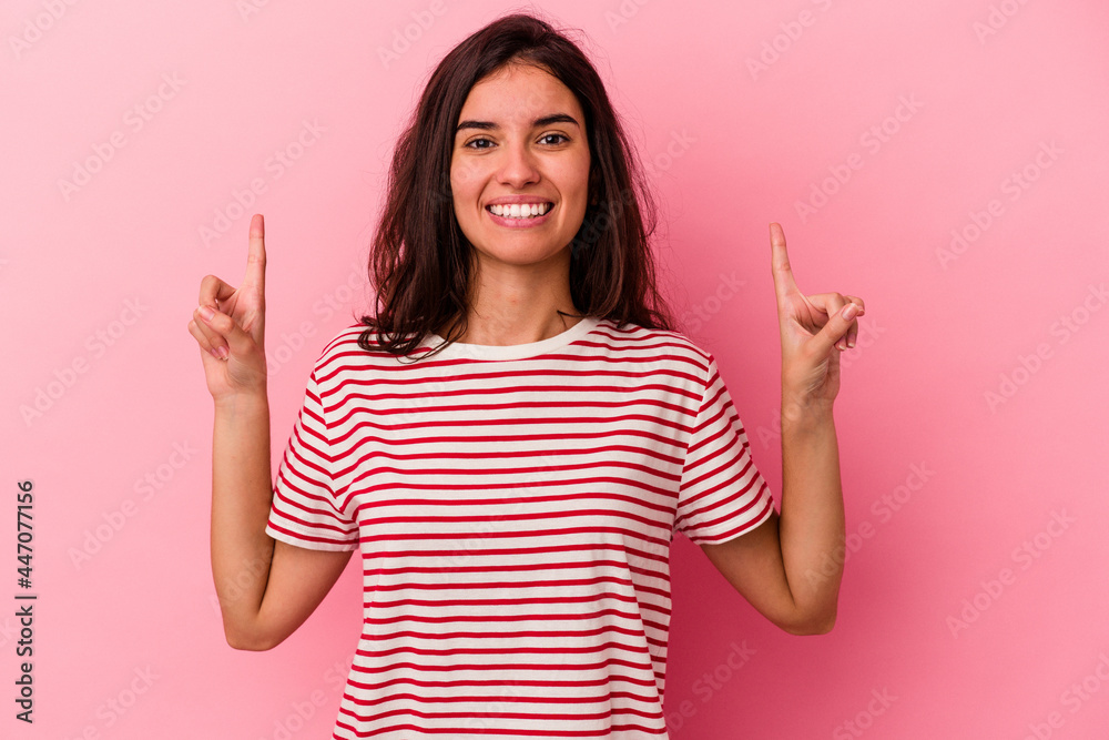 Young caucasian woman isolated on pink background indicates with both fore fingers up showing a blank space. Young caucasian woman isolated on pink background indicates with both fore fingers up showing a blank space.