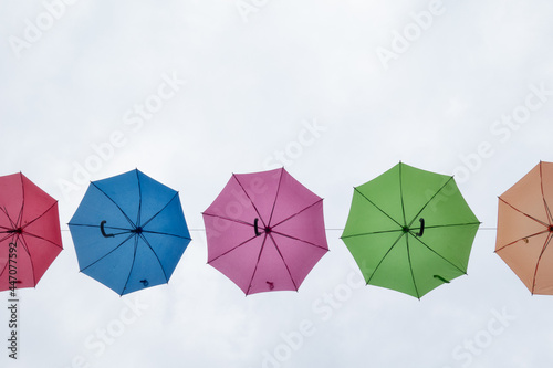 Three colorful umbrellas floating in the cloudy sky