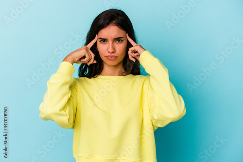Young caucasian woman isolated on blue background focused on a task, keeping forefingers pointing head.