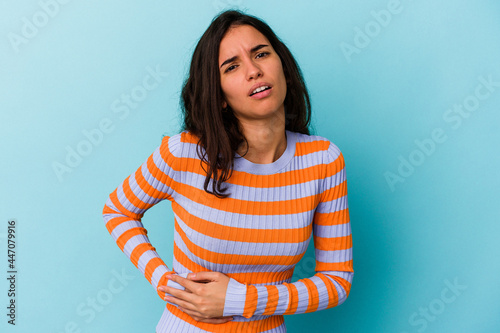 Young caucasian woman isolated on blue background having a liver pain, stomach ache.