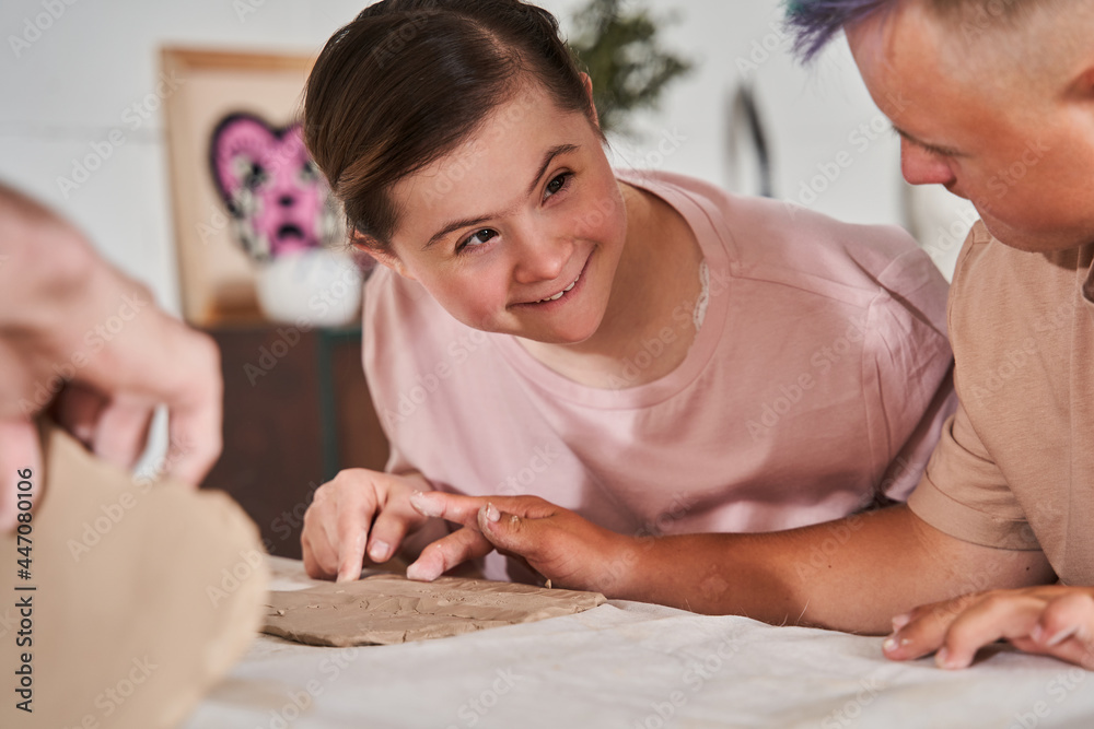 Boy with special needs looking how his friend sculpting from the clay at the master class Boy with special needs looking how his friend sculpting from the clay at the master class