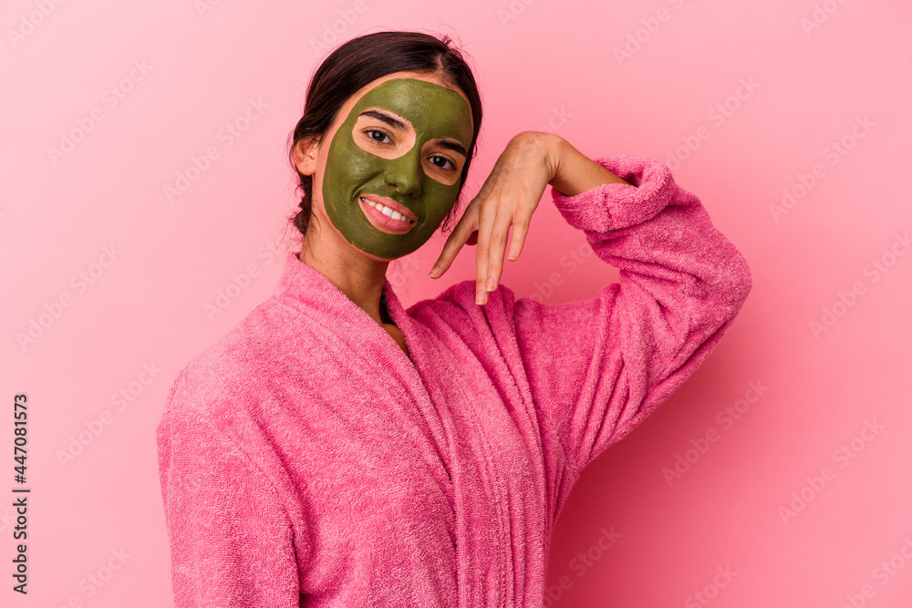 Young caucasian woman wearing a bathrobe and facial mask isolated on pink background Young caucasian woman wearing a bathrobe and facial mask isolated on pink background