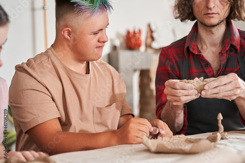 Sculptor preparing shape of the future plate and showing it to his students with special needs