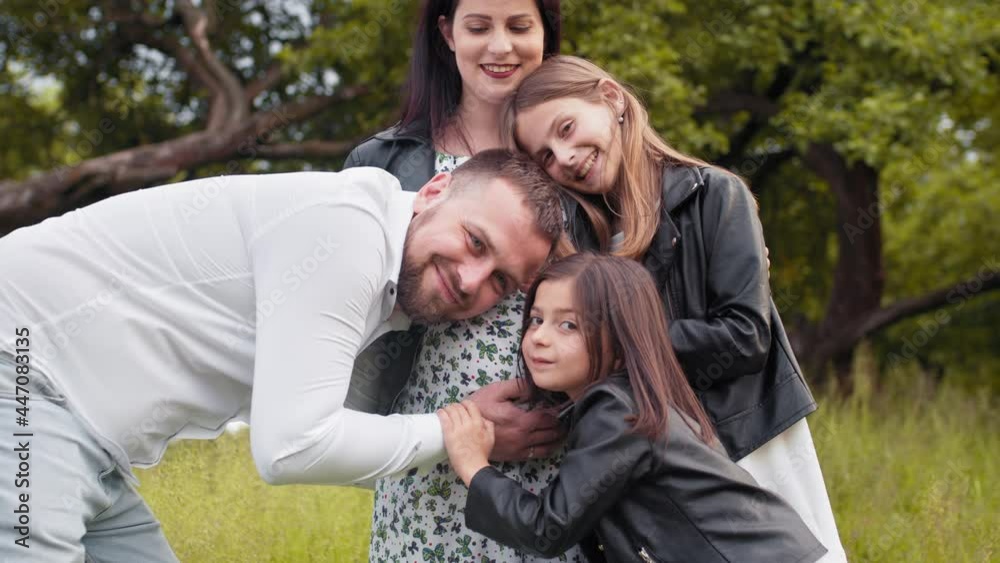 Handsome man and two cute sisters embracing pregnant tummy of beautiful woman. Caucasian family in expectation. Outdoors portrait. Man with two kids embracing pregnant women outdoors Handsome man and two cute sisters embracing pregnant tummy of beautiful woman. Caucasian family in expectation. Outdoors portrait. Man with two kids embracing pregnant women outdoors