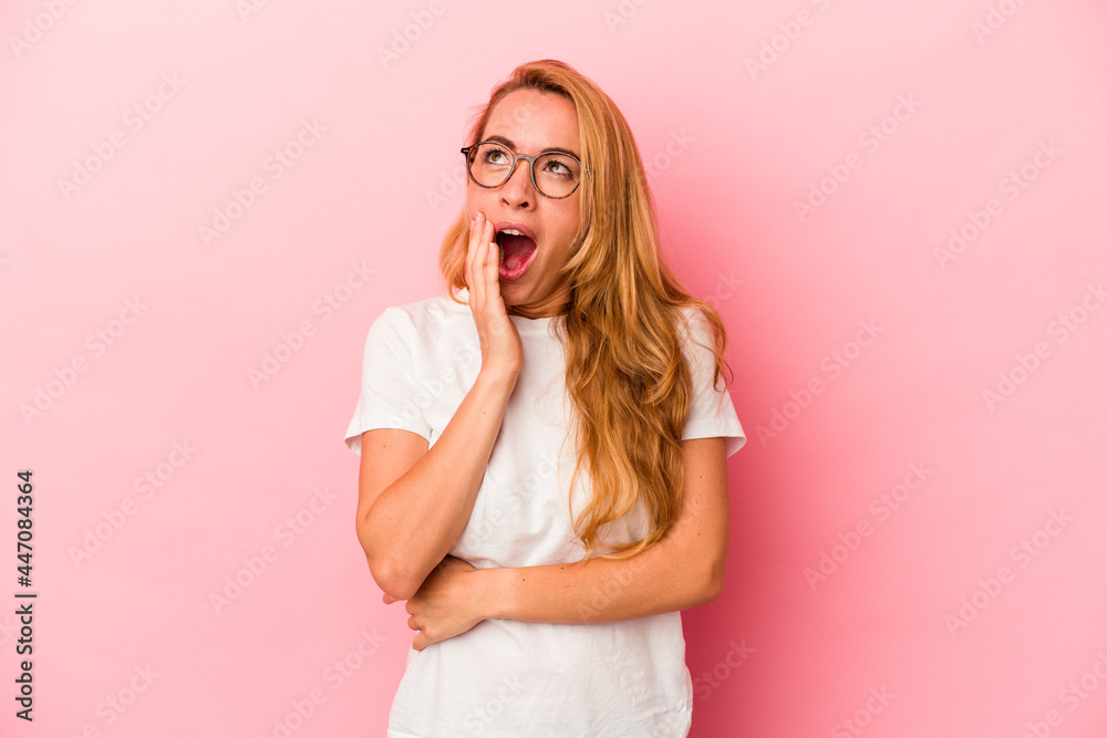 Caucasian blonde woman isolated on pink background yawning showing a tired gesture covering mouth with hand. Caucasian blonde woman isolated on pink background yawning showing a tired gesture covering mouth with hand.