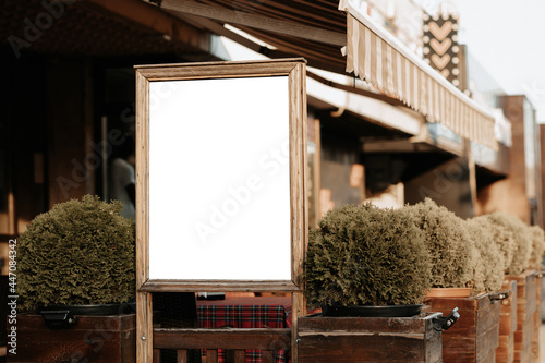 Mock-up for advertising and ads. Outdoor banner for ads and offers. Blank white outdoor advertising stand. Clear street signage board placed by an outdoor dinning area of a restaurant. 