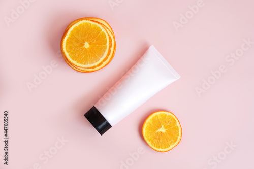 Mockup of pink squeeze bottle plastic tube with black cap and orange slices on pink background. Bottle for branding and label. Natural organic cosmetics. Percent sign concept