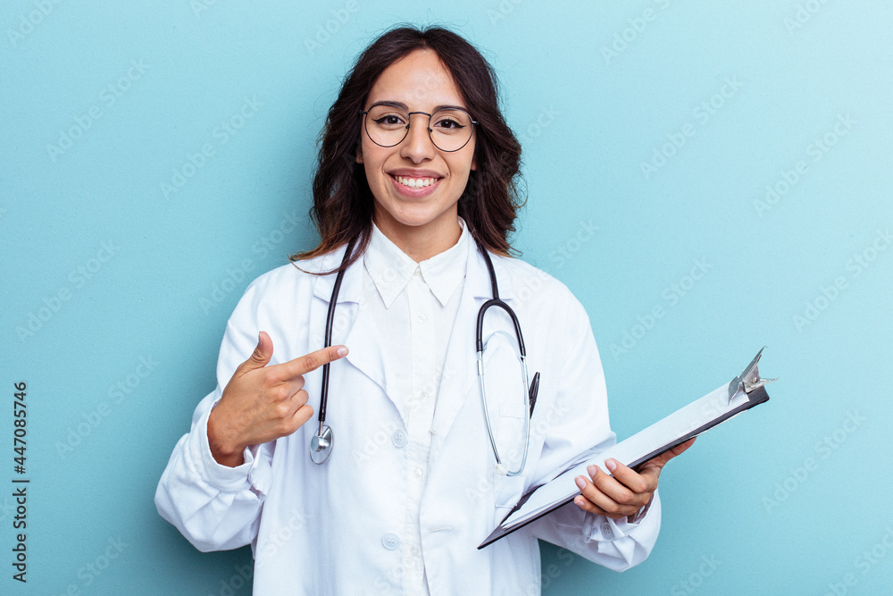 Young doctor mexican woman isolated on blue background person pointing by hand to a shirt copy space, proud and confident Young doctor mexican woman isolated on blue background person pointing by hand to a shirt copy space, proud and confident