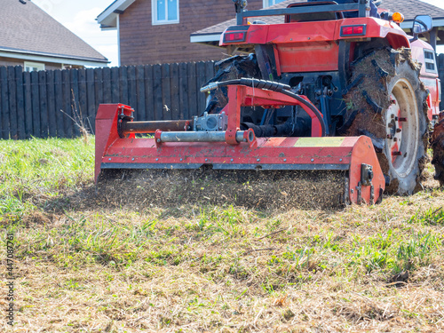 close-up of a tractor with a chain mower chopping dry grass. Maintenance of the territory, mulching of grass, agricultural machinery. photo