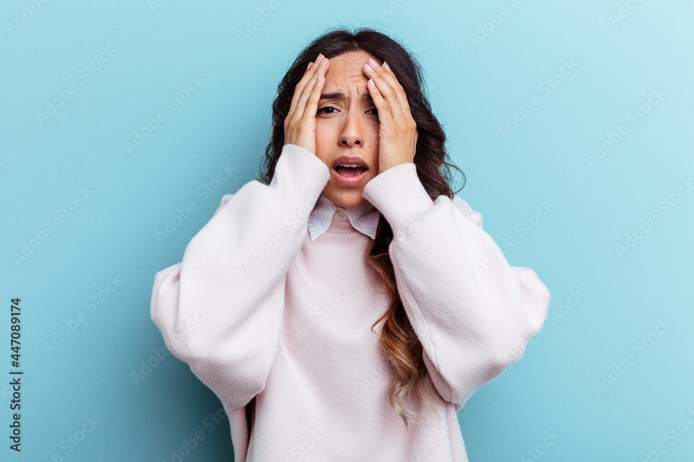 Young mexican woman isolated on blue background having fun covering half of face with palm. Young mexican woman isolated on blue background having fun covering half of face with palm.