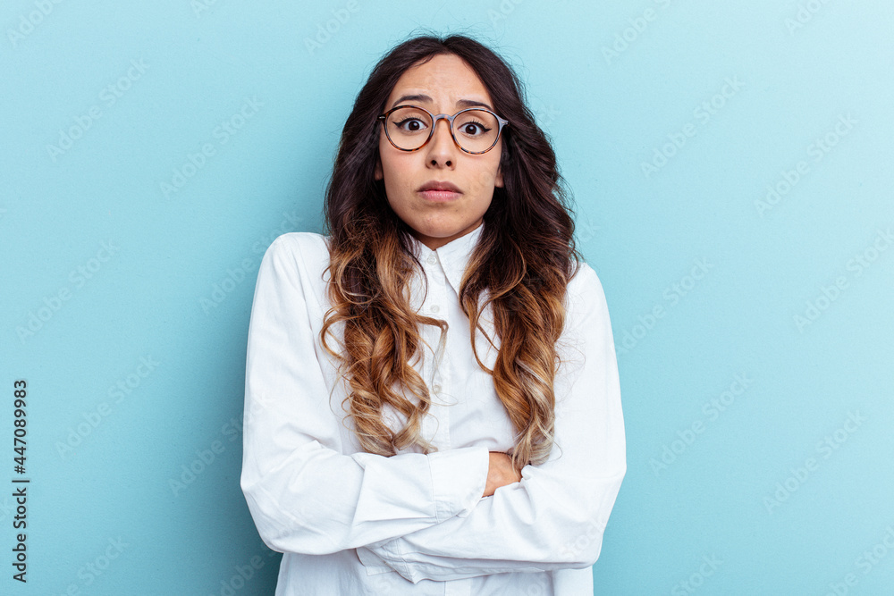 Young mexican woman isolated on blue background shrugs shoulders and open eyes confused. Young mexican woman isolated on blue background shrugs shoulders and open eyes confused.