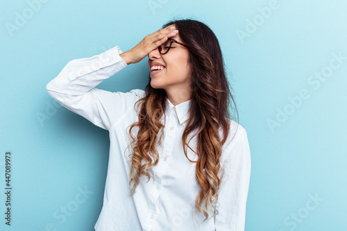 Young mexican woman isolated on blue background laughs joyfully keeping hands on head. Happiness concept.
