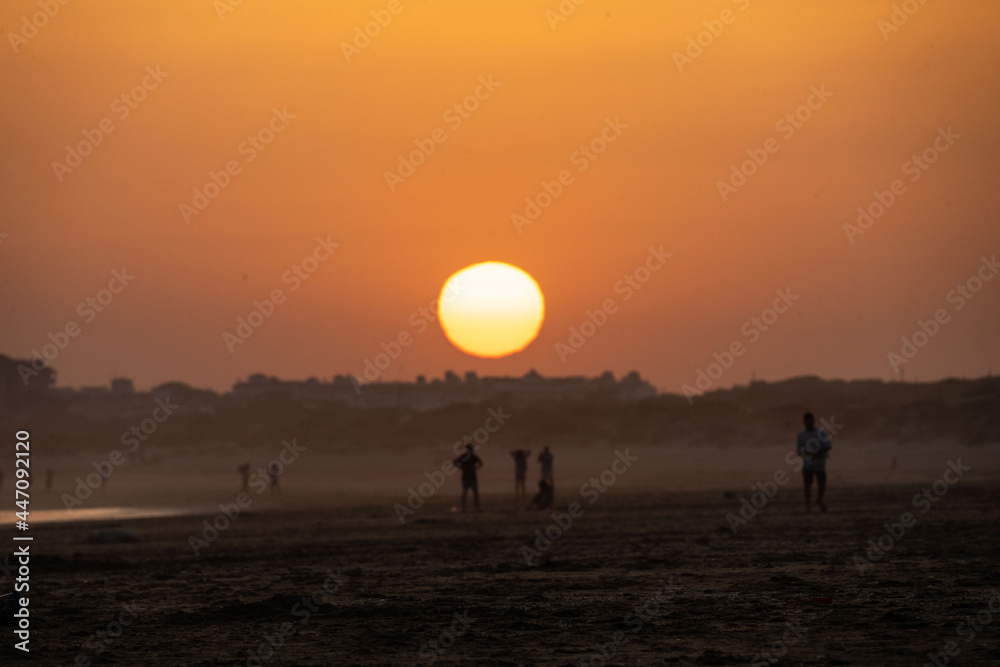 sunset on the beach of huelva with silhouettes of people