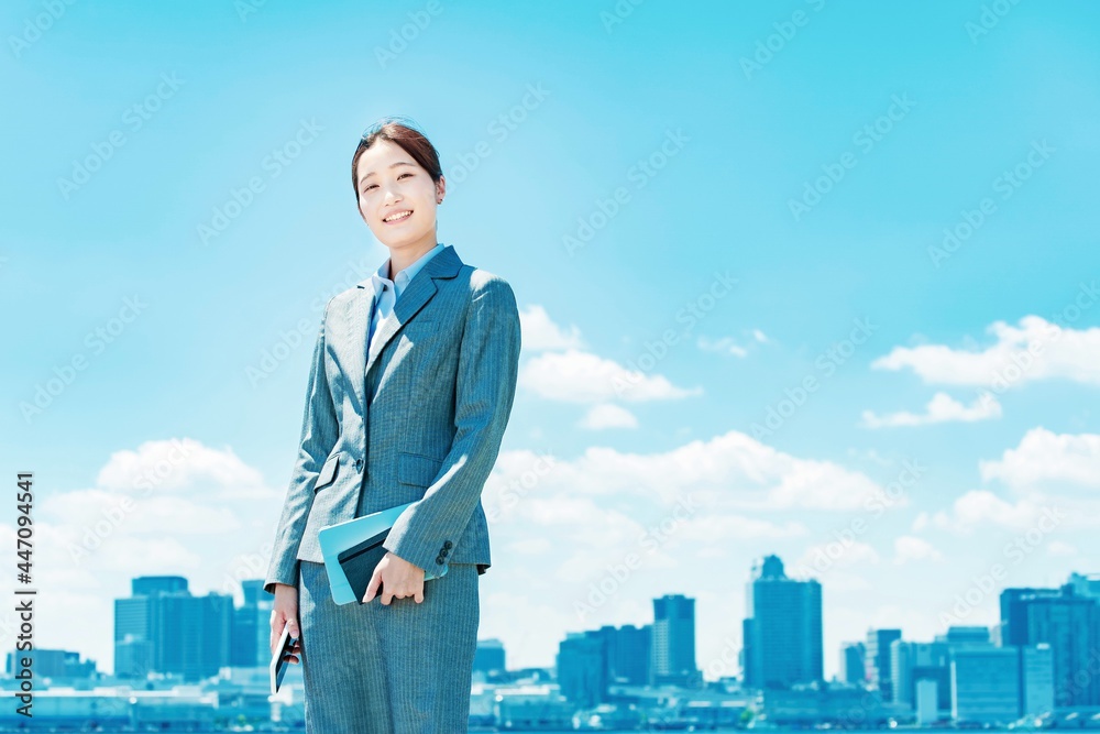 都心と青空を背景に立つ若いビジネスウーマン 都心と青空を背景に立つ若いビジネスウーマン