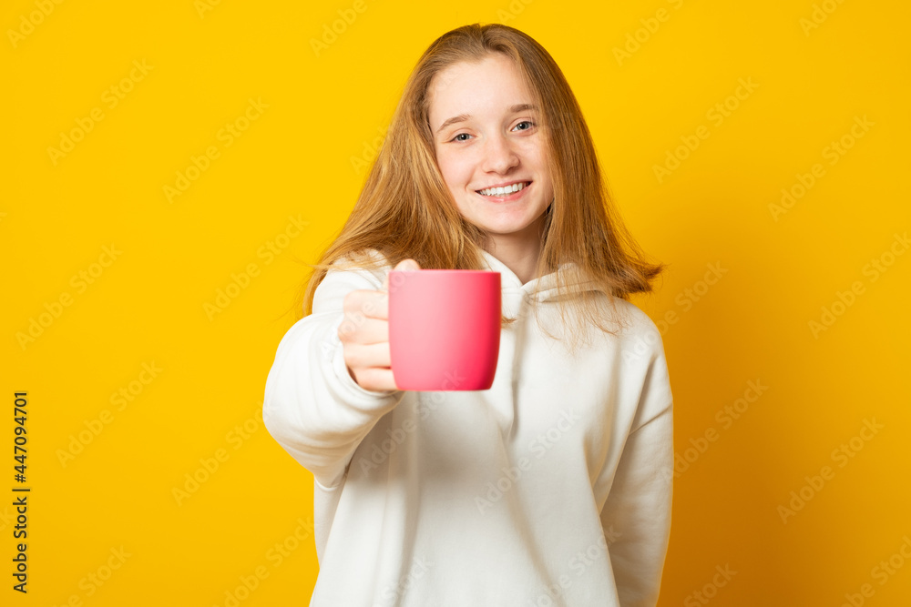 Portrait of young woman giving hot coffee or tea beverage to camera on yellow background. Portrait of young woman giving hot coffee or tea beverage to camera on yellow background.