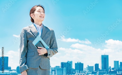 都心と青空を背景に立つ若いビジネスウーマン © maru54