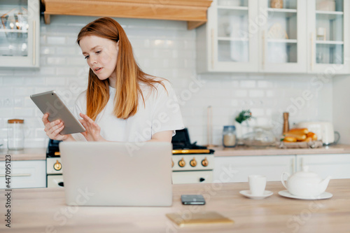 A smart student does tasks remotely online on the Internet. A young female freelance blogger works at home on a laptop. Writes a letter to clients by email.