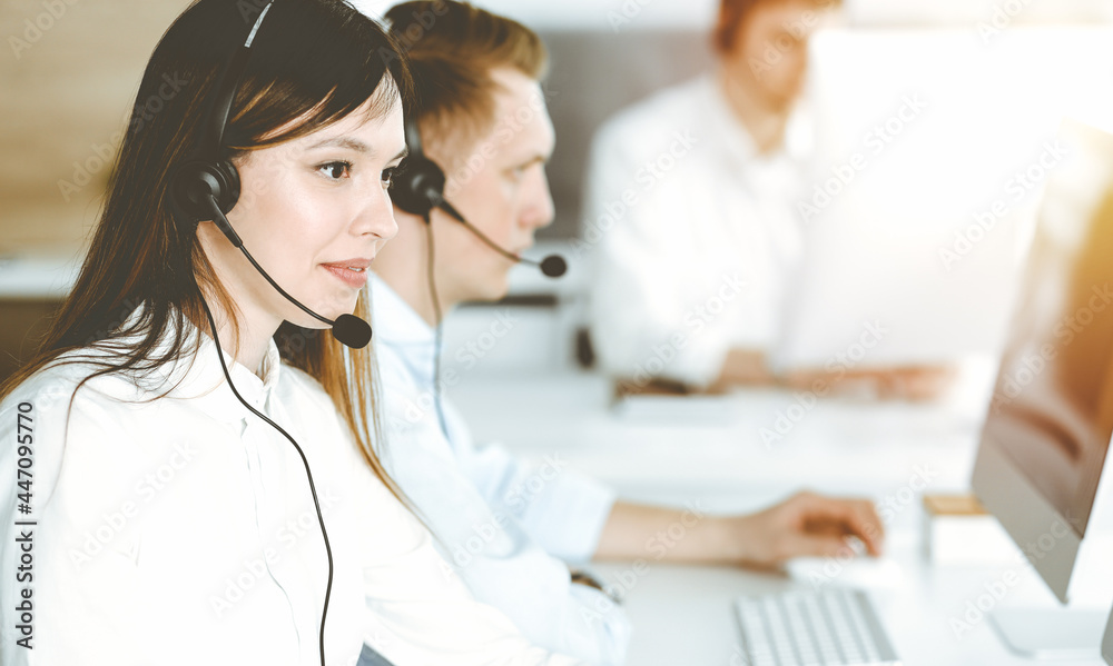 Asian woman working at customer service office. Business concept. Group of diverse operators at work in sunny call center. Asian woman working at customer service office. Business concept. Group of diverse operators at work in sunny call center.