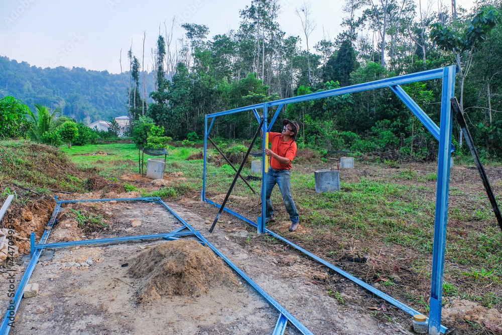Fototapeta premium Gardeners use cordless screwdriver and spirit level while building nursery structures from c channel steel in the garden.