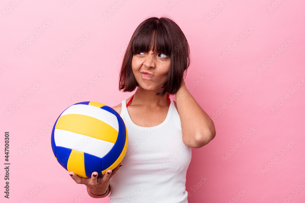 Young mixed race woman playing volleyball isolated on pink background touching back of head, thinking and making a choice.