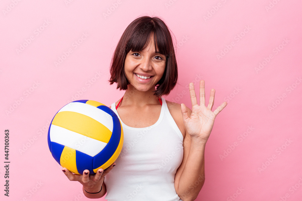 Young mixed race woman playing volleyball isolated on pink background smiling cheerful showing number five with fingers. Young mixed race woman playing volleyball isolated on pink background smiling cheerful showing number five with fingers.