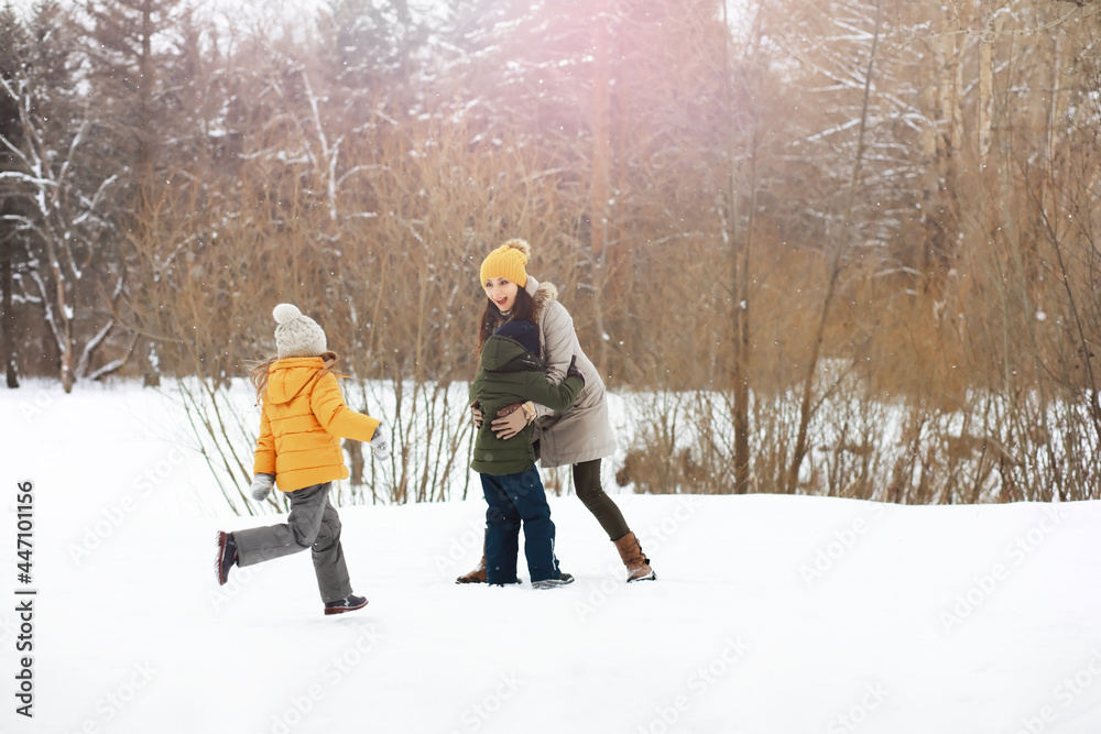 Happy family playing and laughing in winter outdoors in the snow. City park winter day.