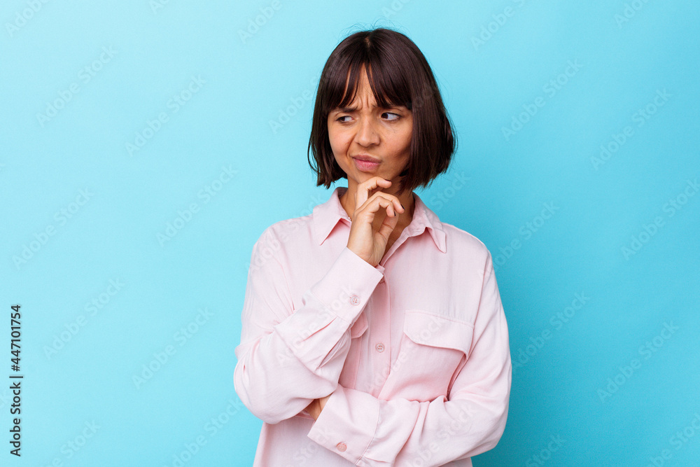 Young mixed race woman isolated on blue background looking sideways with doubtful and skeptical expression. Young mixed race woman isolated on blue background looking sideways with doubtful and skeptical expression.