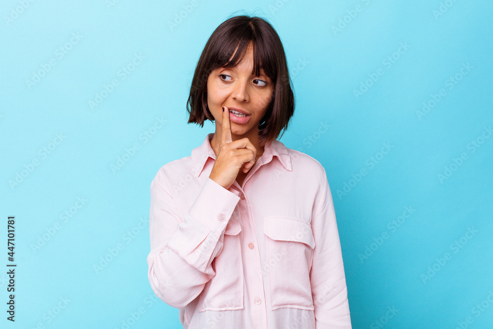 Young mixed race woman isolated on blue background looking sideways with doubtful and skeptical expression. Young mixed race woman isolated on blue background looking sideways with doubtful and skeptical expression.