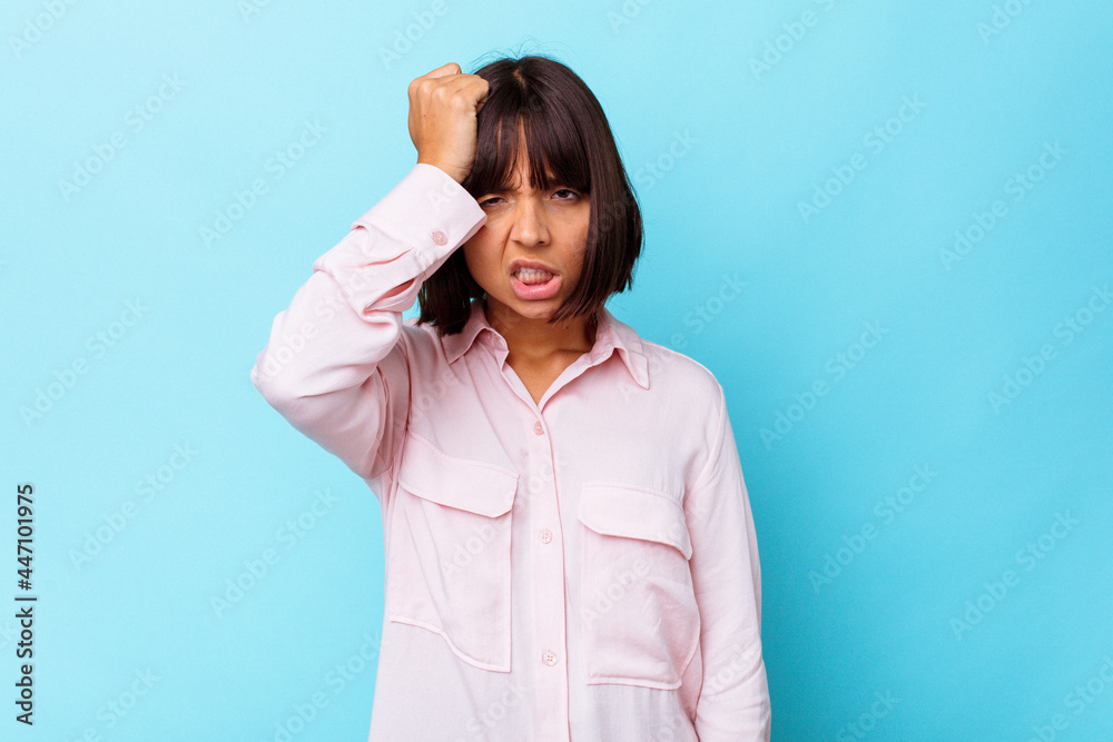 Young mixed race woman isolated on blue background forgetting something, slapping forehead with palm and closing eyes. Young mixed race woman isolated on blue background forgetting something, slapping forehead with palm and closing eyes.